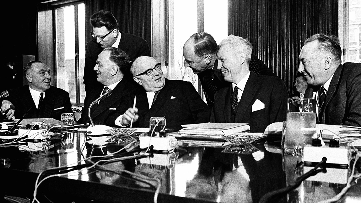 Foto en blanco y negro de los dirigentes de la UE, sentados a una mesa conversando.