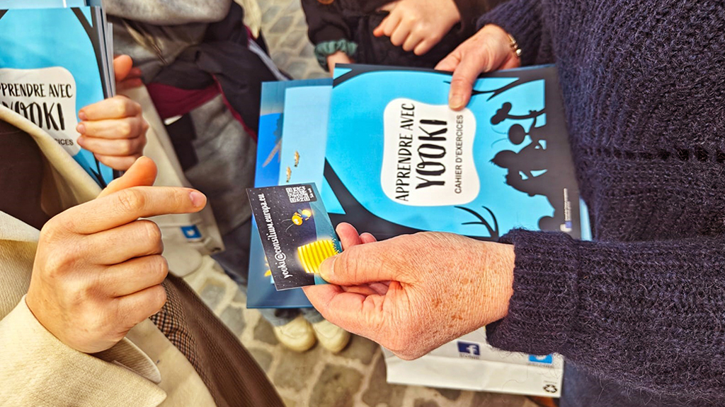 Vizitatori care țin în mână materiale educaționale despre UE la ediția din 2024 a Foire du Livre, Bruxelles